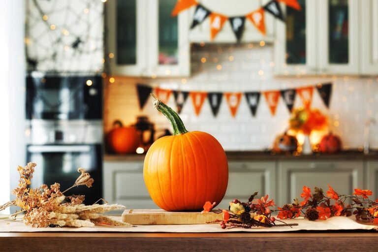 Ambientazione autunnale con rami, foglie e zucca da intagliare per Halloween sul tavolo di legno in cucina