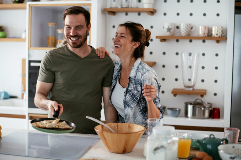 Marito e moglie cucinanino pancake a casa