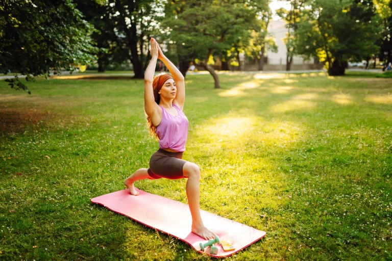 Giovane donna nella posizione yoga del saluto al sole su un prato. Stile di vita attivo